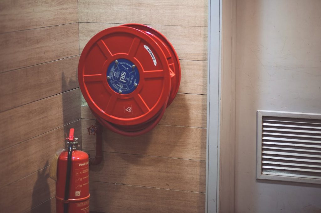 red-fire-extinguisher-below-hose-reel-189474 Red fire hose reel and extinguisher inside a building corner.